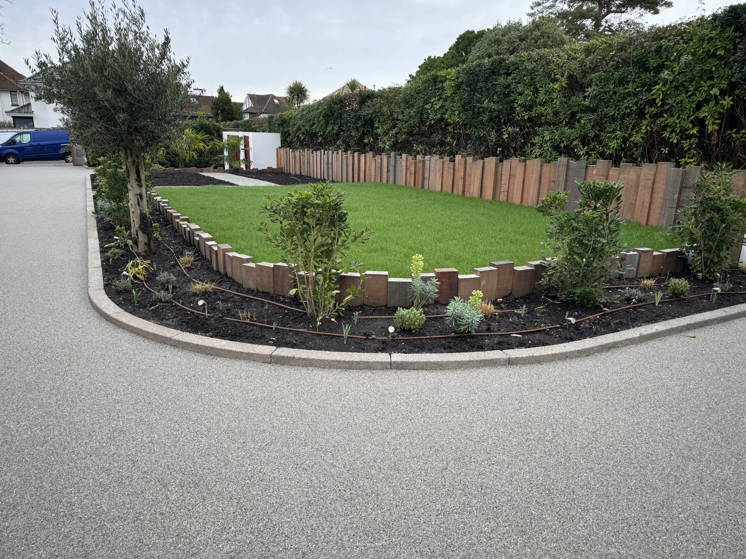 A landscaped area with grass, a flower border and an ornate fence